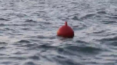 Sakin deniz suyunun yüzeyinde yavaşça yüzen şamandıra. Bir turuncu güvenlik şamandırası alacakaranlıkta denizin yüzeyinde sürüklenir.. 