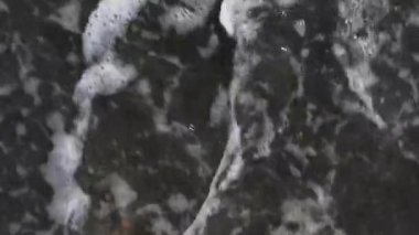 Huzurlu bir insan ayağı sahilde su dalgalarıyla yumuşak ve sıcak kuma batıyor. Gün batımında kumsaldaki sıcak kumsalda rahat ayaklar..