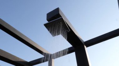 Modern açık hava duş başlığı açık mavi gökyüzüne su dökerek, minimalist tasarımı ile Black Metal yapısından akan, ferahlatıcı yaz rahatlama anını yakalıyor.