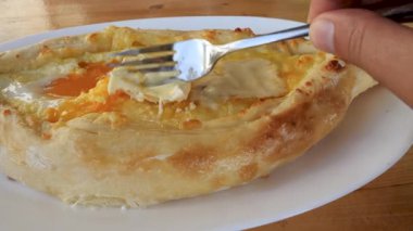 Sıcak khachapuri, erimiş peynir ve çiğ yumurta sarısı ile servis edilir..