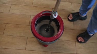 Profesyonel hademe ahşap zemini paspasla temizliyor. Ev içinde temizlik tekniği uyguluyor.