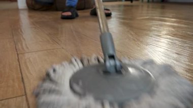 Profesyonel temizlikçi düzenli olarak fayanslı zemini paspaslıyor, temizlik aletini çeviriyor ve kusursuz, hijyenik bir yüzey sağlıyor.