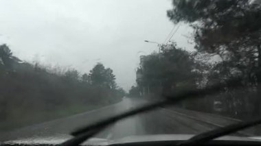 Silecekler yağmuru sileceklerden temizlerken ıslak bir yolda iskan binasına doğru sürüyor.