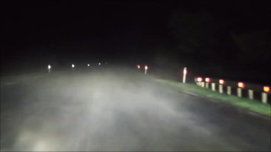 Kırsal karanlığın içinden geçen farlar, puslu virajlı yolları, ıssız yolları ve gece manzaralarını ortaya çıkarıyor. Gizli atmosferik gerilim.