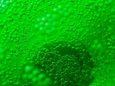 Çok sayıda kabarcığın canlı yeşil karbonatlı bir sıvıda yükselmesi dinamik ve canlandırıcı bir görsel doku yaratır.