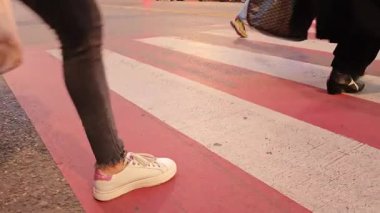 Vatandaşlar pembe beyaz yaya geçidini geçiyor.