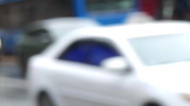 Bulanık arabalar ve otobüsler ıslak bir yolda ilerliyor.