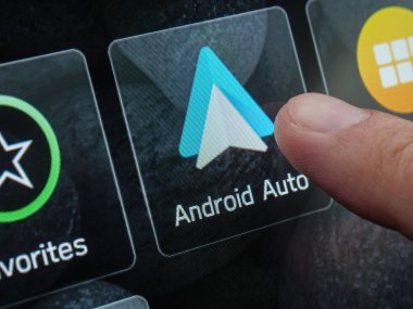Aracın dokunmatik gösterge panelinde dijital navigasyon kontrollerini gösteren android otomatik arayüze dokunan parmak. Tiflis, Gürcistan - 31 Mart 2025.