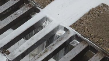 Kaldırımdaki rögar borusuna akan beyaz köpük.