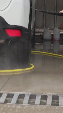 Araba yıkama işçisi yüksek basınçlı su jeti kullanıyor
