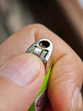 Yeşil bir çakmağı yakmak üzere olan bir el, bir alev yaratma beklentisini yakalıyor.