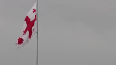 Metal bir direkte rüzgarda sallanan Gürcistan ulusal bayrağı