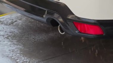 Yüksek basınçlı su püskürtüsüyle temizlenen bir araba egzoz borusu.