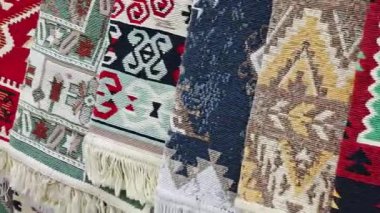 Çeşitli desenlere ve renklere sahip geleneksel halı ve halılar yan yana asılıyor