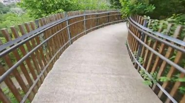 Pürüzsüz beton yol, ahşap bir çitle çevrili canlı yeşil bir arazide esiyor.