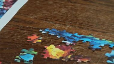 Elleri, çizik ahşap bir masada canlı bir yapboz yapıyor.