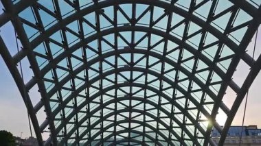 Güneş ışığı Tiflis, Georgia 'daki barış köprüsünün cam tavanına yansıyor.