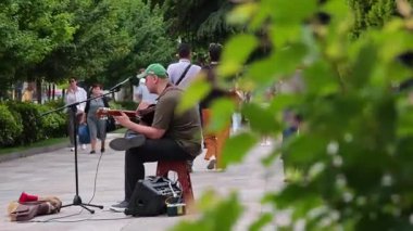 Canlı bir şehir parkında akustik gitar çalan müzisyen. Tiflis, Gürcistan - 27 Mayıs 2025.