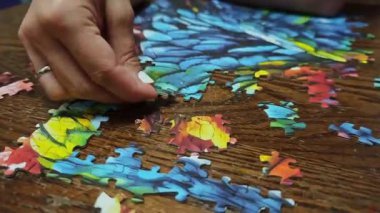 Ahşap bir masada renkli bir yapboz yapan kadın.