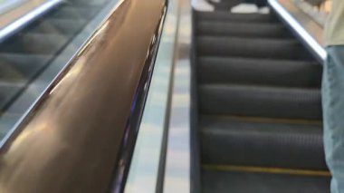 Dağınık bir alışveriş merkezinde yürüyen merdiven tırabzanı yukarı doğru hareket ediyor.