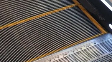 Metal yürüyen merdivenler bir alışveriş merkezinde ya da havaalanında yukarı doğru hareket ediyor.