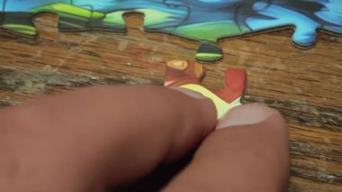 Tahta bir masanın üzerindeki renkli yapboz parçalarını birleştiren elleri kapatın.