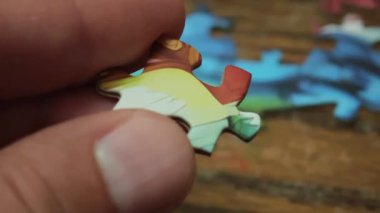 Ahşap bir masa üzerindeki renkli bir yapbozun iki uyumlu parçasını birbirine bağlayan ellerinizi kapatın.