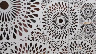 Karmaşık dairesel desenler beyaz metal bir cepheyi süslüyor, modern mimari tasarımı sergiliyor.