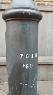 Tuğla duvar ve gökyüzüne dayanan yıpranmış bir sokak lambasının ayrıntılı ayrıntılarını ortaya çıkarıyor.