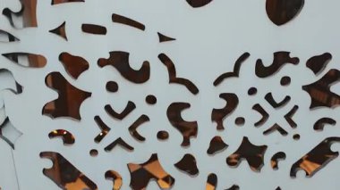 Beyaz ahşap panellere oyulmuş süs tasarımları karmaşık ve dekoratif bir görsel efekt yaratıyor.