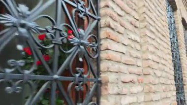 Tarihi bir binanın tuğla cephesini süsleyen dekoratif işlenmiş demir ızgaraların yakın çekim görüntüsü