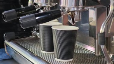 Barista profesyonel espresso makinesi kullanarak iki paket kahve yapıyor.