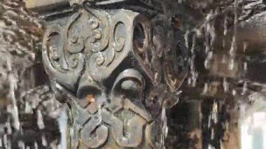 Su zarif bir şekilde oyulmuş çeşme sütununun üzerine dökülür.