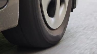 Artan hızda asfalt üzerinde dönen bir araba tekerleğinin montajını kapat