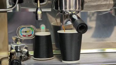 Profesyonel kahve makinesi siyah kağıt bardağa espresso dolduruyor.