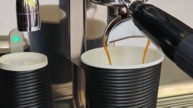 Kahve makinesi kahve bardağına kahve dolduruyor.