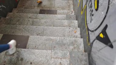 Yeraltı merdivenleriyle kaplı bir grafiti üzerinde yürüyen insanlar. Tiflis, Gürcistan - 26 Mayıs 2025.