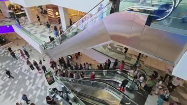 Kalabalık bir alışveriş merkezinde çok sayıda müşteri yürüyen merdivenlere tırmanır. Tiflis, Gürcistan - 8 Haziran 2025.