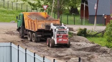Ağır makineler kullanan, çakıl döşeyen ve kırsal arazide gün içinde çalışan toprak taşıma ekipmanlarıyla yol yapımı devam ediyor. Tsemi, Gürcistan - 6 Haziran 2025.