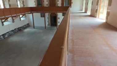 Ahşap korkuluklar boyunca pürüzsüz bir hareket. Kocaman boş bir oda, kemerli pencereler ve kapılar.