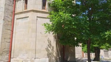 Berrak mavi gökyüzüne karşı heybetli bir kilise kulesi. Huzurlu bir ortamda yemyeşil ağaçlarla çevrili.