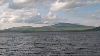 Dramatik güneş ışığı bulutlara nüfuz ediyor, dağlık araziyi aydınlatıyor. Gürcistan 'ın dağlık kesimindeki Paravani Gölü' nü çevreleyen huzur verici manzarayı aydınlatıyor.