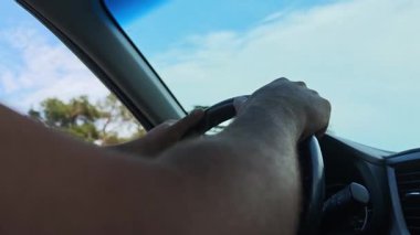 Güneşli bir günde araba kullanırken direksiyon tutan sürücülerin yakın çekimi.