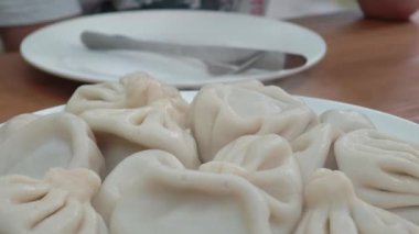 Taze pişmiş khinkali, geleneksel Gürcistan hamur tatlısı, beyaz bir tabakta servis ediliyor, tadını çıkarmaya hazır.