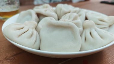 Buharda pişirilmiş Khinkali, geleneksel Gürcistan hamur tatlısı, beyaz bir tabakta servis ediliyor, tadını çıkarmaya hazır.