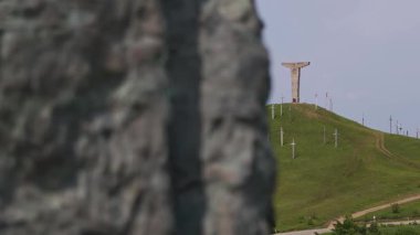 Bulanık bir ön plandan Gürcistan 'daki yeşil bir tepedeki Didgori savaş anıtına kayan odaklanma