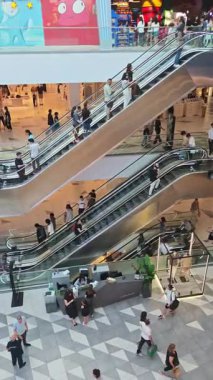 Kalabalık modern bir alışveriş merkezinde yürüyen merdivenlere doğru ilerliyor. Tiflis, Gürcistan - 8 Haziran 2025.