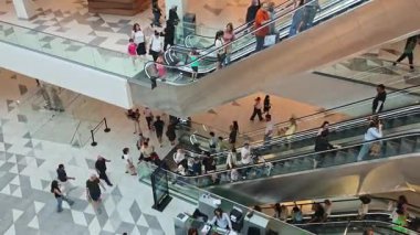 Modern bir alışveriş merkezinde yürüyen merdivene binen müşteriler. Tiflis, Gürcistan - 8 Haziran 2025.