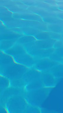 Güneş ışığında pırıl pırıl parlayan kristal berrak havuz suyu yüzeyi.