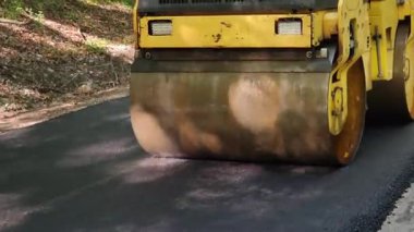 Sarı yol silindiri yeni bir yolda sıcak asfaltı dümdüz ediyor